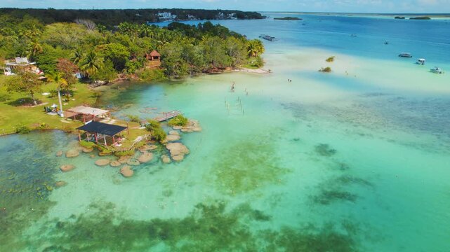 Sunny day view of Bacalar lagoon waterfront with boats and beach in Mexico