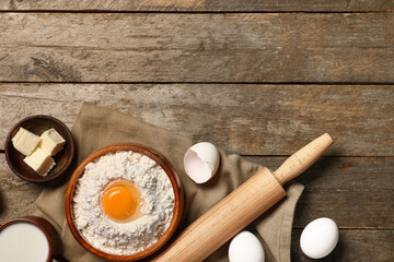Composition with ingredients for baking, rolling pin and napkin on wooden background