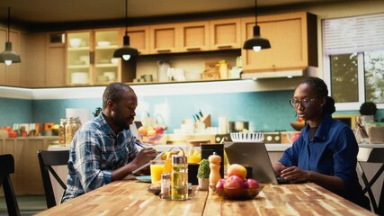 African American couple writing a grocery list together on a laptop. Man and woman planning shopping for essentials, groceries and household products online, healthy eating habits. Camera A. - Powered by Adobe