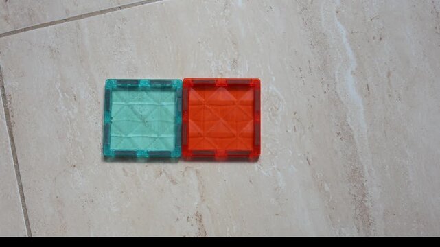 Close-up of hands shaping translucent colorful cube pieces into various forms