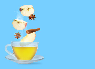 Health boosting drink for cold season. Apple pieces, cinnamon and anise falling into cup on light blue background. Space for text