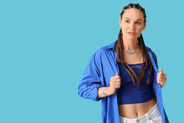 Stylish young woman in shirt with dreadlocks on blue background