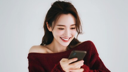 笑顔で楽しそうにスマートフォンを見る、若くて美しい日本人女性