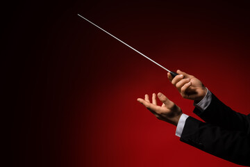 Male conductor's hands on dark red background