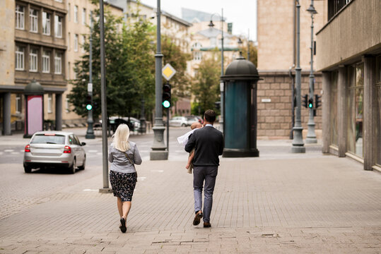 Urban morning walk as a couple with a child in a modern city street, showcasing family life, pedestrian lifestyle, and everyday city living in a peaceful downtown environment.