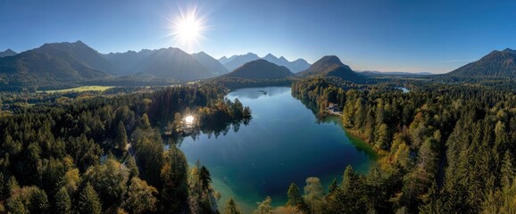 Aerial panoramic of a serene mountain lake surrounded by autumn forests under a radiant sun