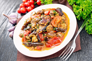 Eggplants with champignons in plate on wooden table