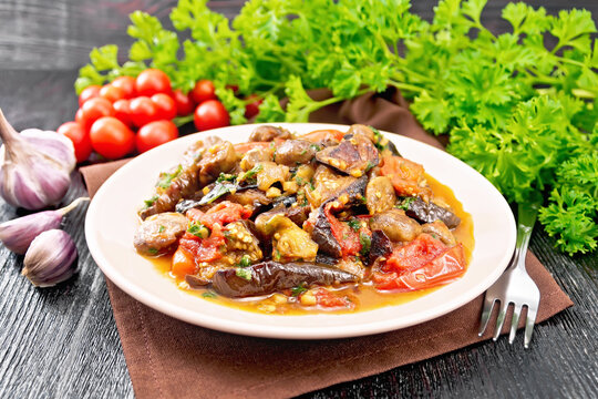 Eggplants with champignons in plate on dark board