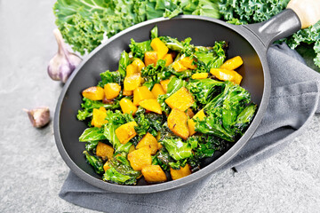 Kale with pumpkin in skillet on granite table