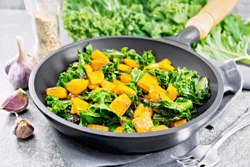 Kale with pumpkin in skillet on stone table
