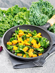 Kale with pumpkin in skillet on granite countertop