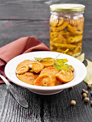 Mushrooms salted in plate on black wooden board