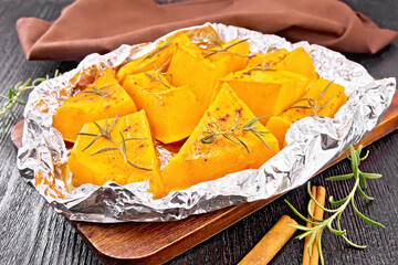 Pumpkin baked in foil on dark board