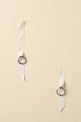 Elegant off-white ribbons with delicate silver rings arranged on a pale background