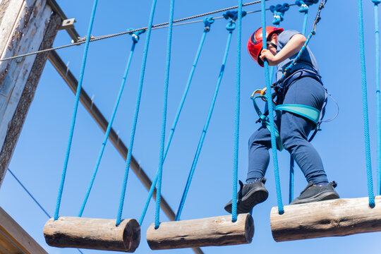 Child boy in Protective Gear Navigating a High Ropes Course in adventure park 