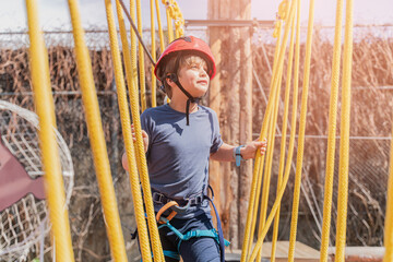 Child boy in Protective Gear Navigating a High Ropes Course in adventure park 