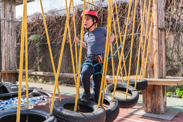 Child boy in Protective Gear Navigating a High Ropes Course in adventure park 
