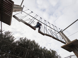 Child boy in Protective Gear Navigating a High Ropes Course in adventure park 