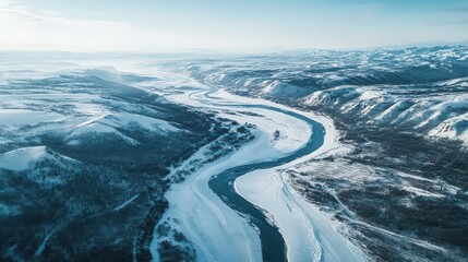 Aerial view of a river winding through a snowy mountain landscape