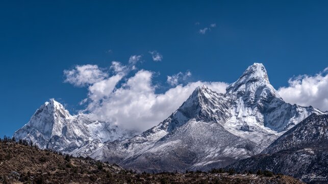 A panoramic view of the Himalayas with the majestic Ama Dablam peak and surrounding snow-capped mountains under clear blue skies. The scene highlights the natural beauty and textures of the landscape.