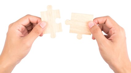 Two hands hold wooden puzzle pieces close together, preparing to connect them. The background is plain, highlighting the focus on the hands and puzzle pieces in a serene environment.