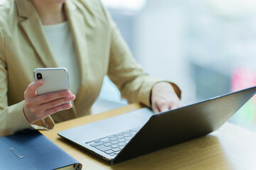 パソコンとスマートフォンを使うビジネスパーソン