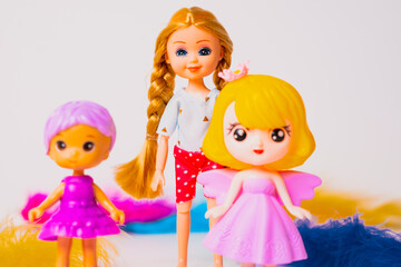 Colorful dolls standing together on a white background with bright feathers around them