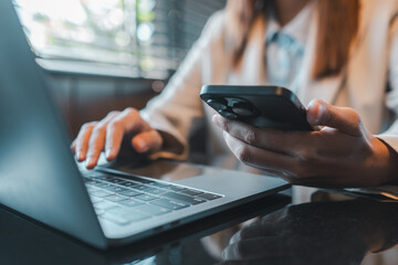 Close-up of a person multitasking with a smartphone and laptop, showcasing modern business technology and productivity.