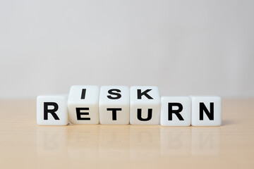 Flipping of dice which print screen risk and return wording. Investment concept about balance between risk and return