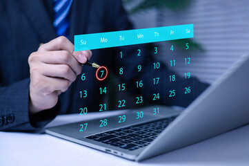 Businessman planning schedule with a digital calendar interface on laptop, highlighting an important date for meeting, reminder, appointment, task management, and efficient time organization.