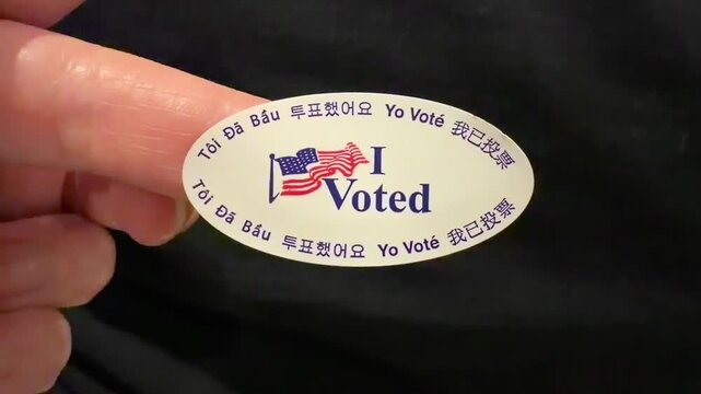 Finger holding up a "I Voted" sticker translated in different languages. 2025 Special Elections in California, USA.