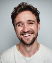 Fototapeta premium Happy smiling young man portrait close up authentic laugh joy emotion natural light studio beard white teeth excitement adult male face