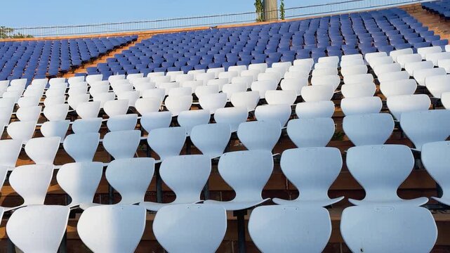 Curved white stadium chairs arranged in rows at outdoor sports venue
