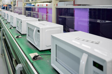 Rows of white microwaves in production line at factory during daytime
