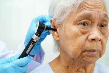 Otolaryngologist or ENT physician doctor examining senior patient ear with otoscope, hearing loss problem.