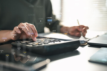 Hands using a calculator and writing financial documents with floating data graphics, representing accounting analysis, tax calculation, investment planning, and professional budgeting management.