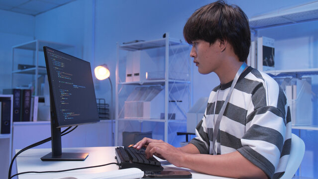 One young male Asian IT freelancer programmer and tech engineer working with computer keyboard, typing software codes for application development and website network system information data in room.