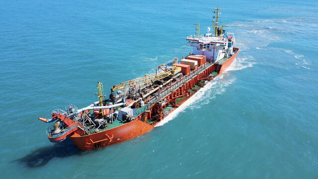 Aerial view of a dredging vessel operating offshore, showing the ship during maritime operation, suction dredger on the coast widening the sand strip beach.