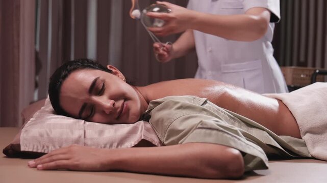 Beauty Latino woman is treated for healthy recovery with cupping therapy by Asian physical muscle doctor, an oriental traditional medicine therapist at a spa clinic, and wellness massaging lifestyle.