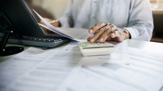close up shot, accountant working in office with documents using calculator to calculate monthly expenses, budget, tax to summarize monthly performance results