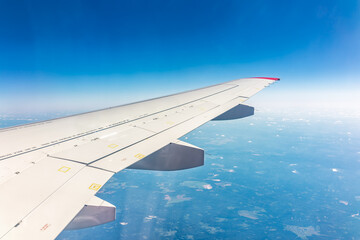 Obraz premium View from the airplane window at a beautiful blue clear sky and the airplane wing