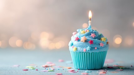Cupcake with pastel blue frosting sprinkled with candy stars candle gently glowing sharp focus on icing ridges soft