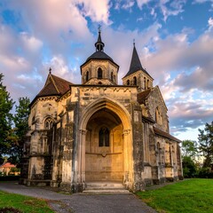 Fototapeta premium An aged stone church basks in golden light against a cloudy sky