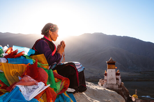 Old woman praying at sunset on top of hill, Tibet