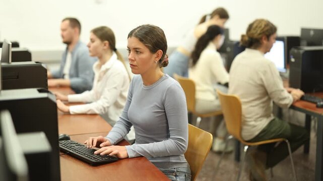 Young woman using computer for work in office with colleagues