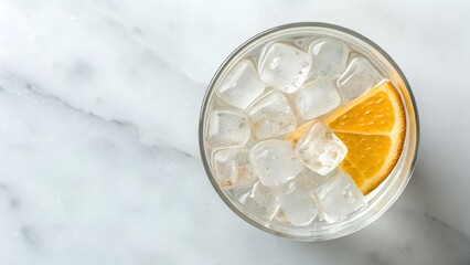 Clear Sparkling Beverage With Orange Slice And Ice Cubes On White Marble Surface Overhead View