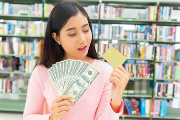 Smiling girl showing platic credit card and holding dollar