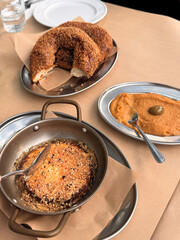traditional greek food on table with round stone baked bread with sesame seeds and spicy dip served on table with brown paper tablecloth