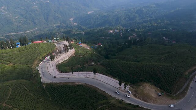 A smooth drone flight captures the verdant scenery of Kanyam's popular tea gardens in Ilam, Nepal, highlighting the scenic highway as it winds through the lush, green landscape. Green tea fresh leaves