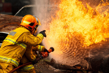 Naklejka premium Firefighters spraying water to control extinguish an intense blaze.